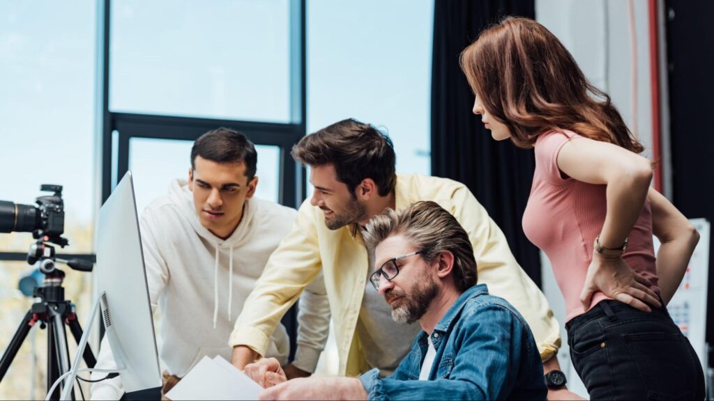 Marketing team collaborating at a desktop computer to review content planning and campaign details for a digital marketing strategy.